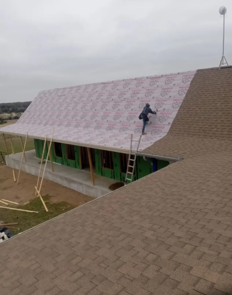 Worker preparing underlayment for a metal roof installation in Oil City